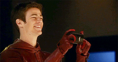 The Flash activates a two-second self timer on his phone, drops it, rejoins his group in a flash to pose for the photo, and then quickly returns to catch the phone.