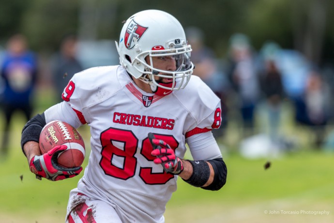 A solid sports photo with superb technical quality and a great depiction of the athlete’s expression. The fans in the background and the great use of depth of field add a lot of atmosphere. Photo: Gridiron Victoria : John Torcasio Photography