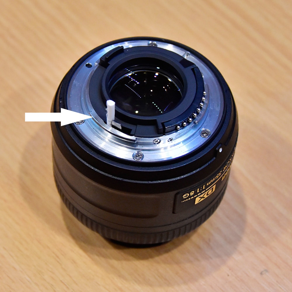 A Nikkor 35 mm lens. Setting the aperture lever with a small roll of paper.