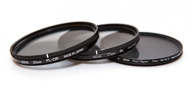 Three polarizing filters. Two are circular, one is linear. On the right is the “slim” version. Note how it is visibly slimmer than the other two. All the filters have a mark on their rotatable part that marks the polarization plane. (Two have a line; the one on the right has a small triangle.)