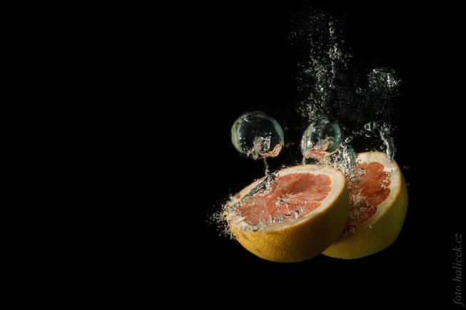 Halved grapefruit. Canon 1000D, EF 75-300 mm při 80 mm, 1/200 s, f/9.0, ISO 100. Background darkened and cleaned up via digital edits.