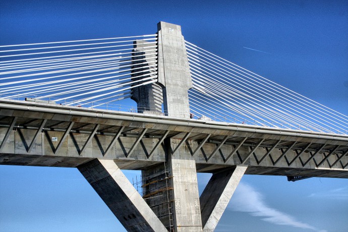 A simple but forceful photo. It captures one portion of a bridge—a pillar. This symmetrical photo is subtly supplemented by the airplane overhead and the figure on the bridge. The coarse grain used also suits it well.