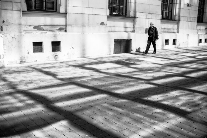 Get rid of the colors and voila, it’s like the person has been peeled out of the picture. This is helped by the contrast of the dark clothing and the brighter background. The line formed by the bases of the houses running parallel to the shadows on the sidewalk adds dynamics and a feeling of motion; its role becomes more important in black-and-white.