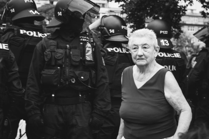 7 Challenges of Reportage Photography: granny ahead of a row of policemen.