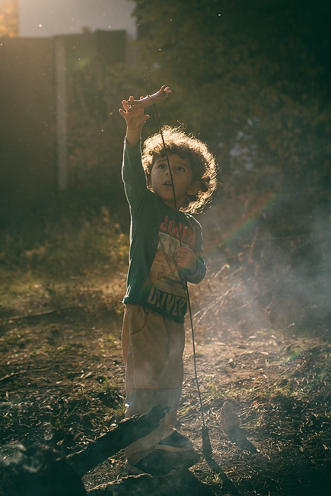 Photographing kids against the light: child toasting sausages.