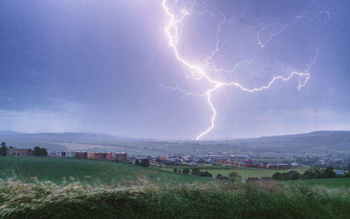 How to photograph lightnings: a lightning with a city in the foreground.