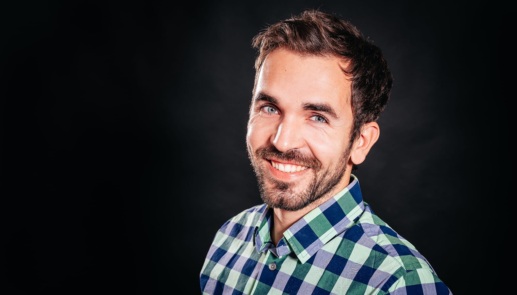 Smiling bearded young man sitting on a tall chair with folded arms on gray  background Stock Photo by diignat